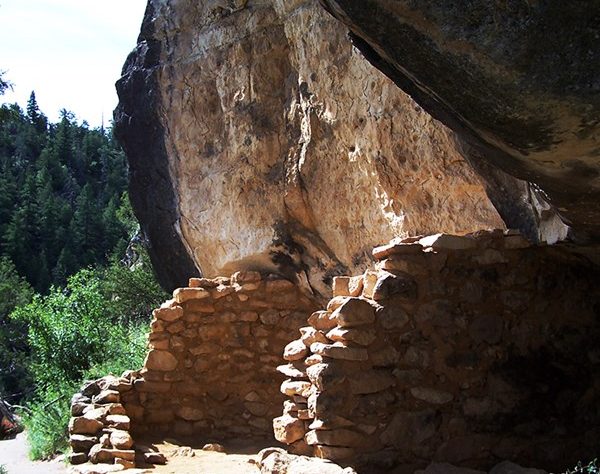 A rocky cave structure surrounded by trees and a pathway