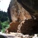 A rocky cave structure surrounded by trees and a pathway