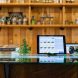 A tablet displaying a digital search interface for cannabis products, surrounded by glass items and books on a counter.